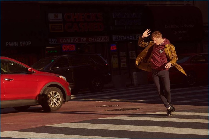 Showing a streetwear-inspired look, Nathan Mitchell wears a H&M car coat with a sweatshirt and skinny fit jeans.