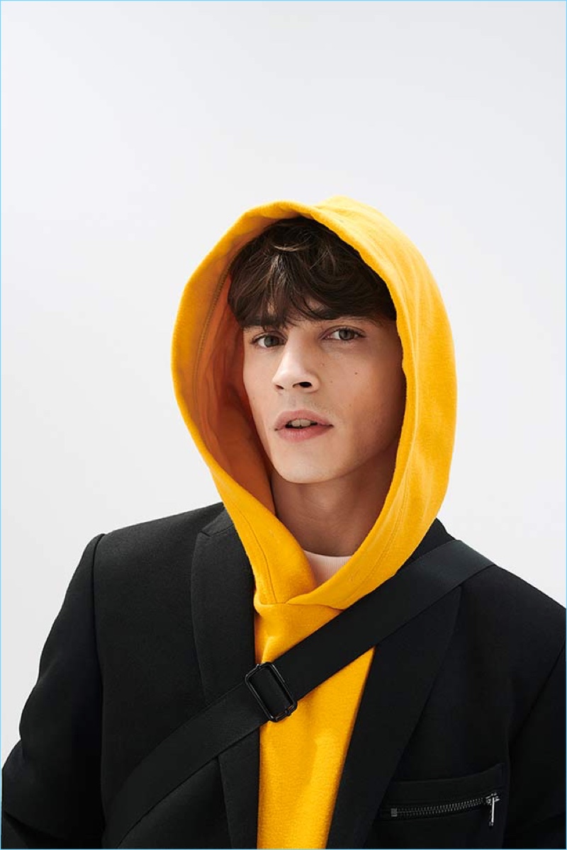 Embracing a pop of color, Adrien Sahores models a yellow hoodie by Reserved.