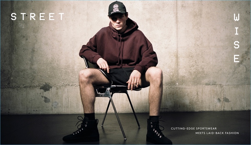 Luka Isaac wears a Yeezy hoodie with a Y-3 baseball cap, Fear of God basketball shorts, and sneakers.