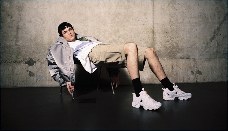 Relaxing, Luka Isaac wears a Sacai bomber jacket, Napa by Martine Rose sweatshirt, Martine Rose cargo shorts, and Vetements sneakers.