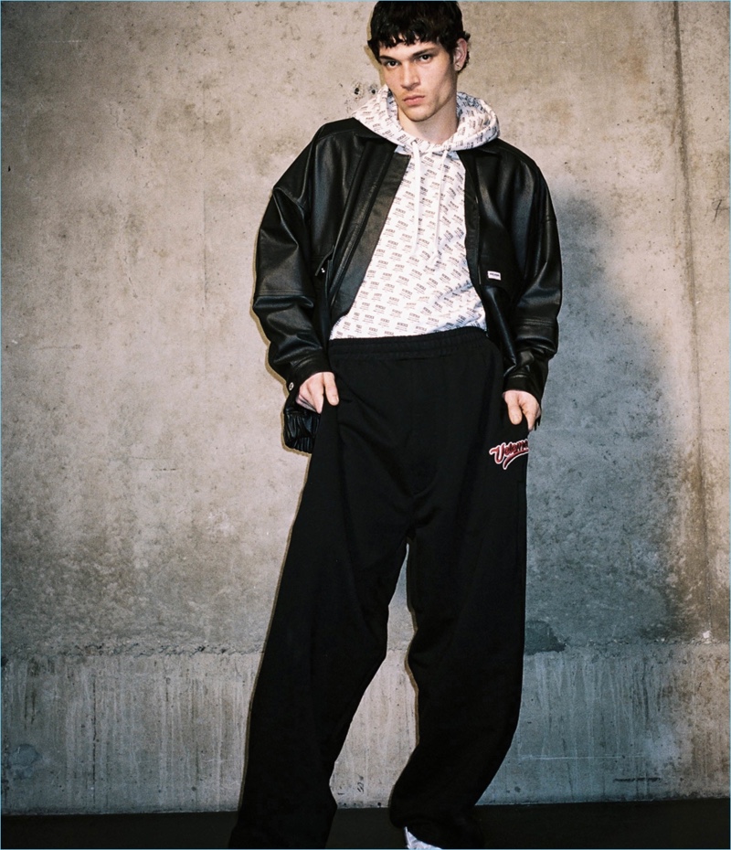 Embracing a streetwear look, Luka Isaac wears a Gucci print sweatshirt, Vetements wide-leg sweatpants, and a leather bomber jacket by Martine Rose.