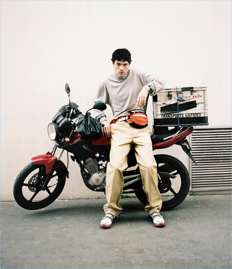 Channeling a geek chic look, Luka Isaac wears a Fear of God long-sleeve tee, Calvin Klein carpenter pants, Prada sneakers, and a Heron Preston belt bag.