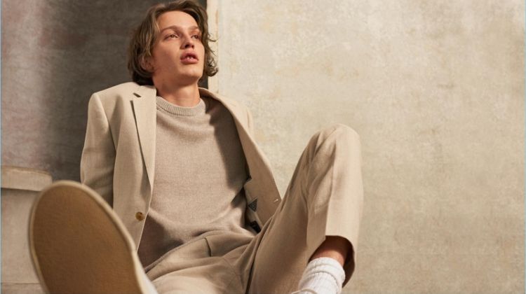 Embracing spring, Lucas Satherley wears a neutral colored look by Club Monaco. He sports a linen crew, blazer, and trousers with Veja sneakers.