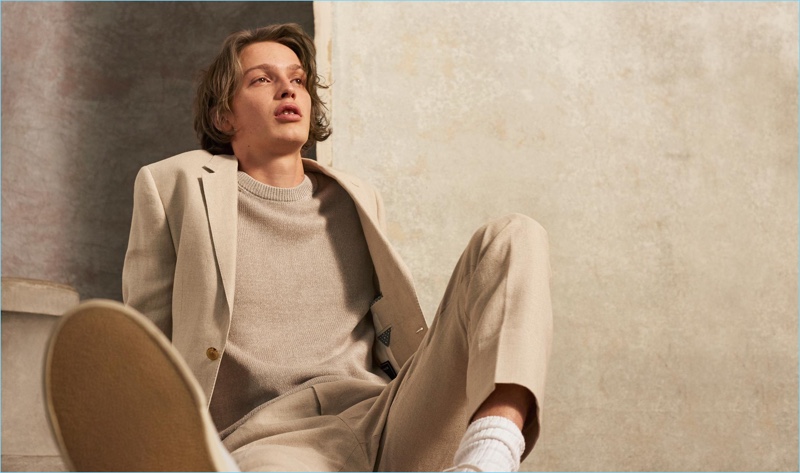 Embracing spring, Lucas Satherley wears a neutral colored look by Club Monaco. He sports a linen crew, blazer, and trousers with Veja sneakers.