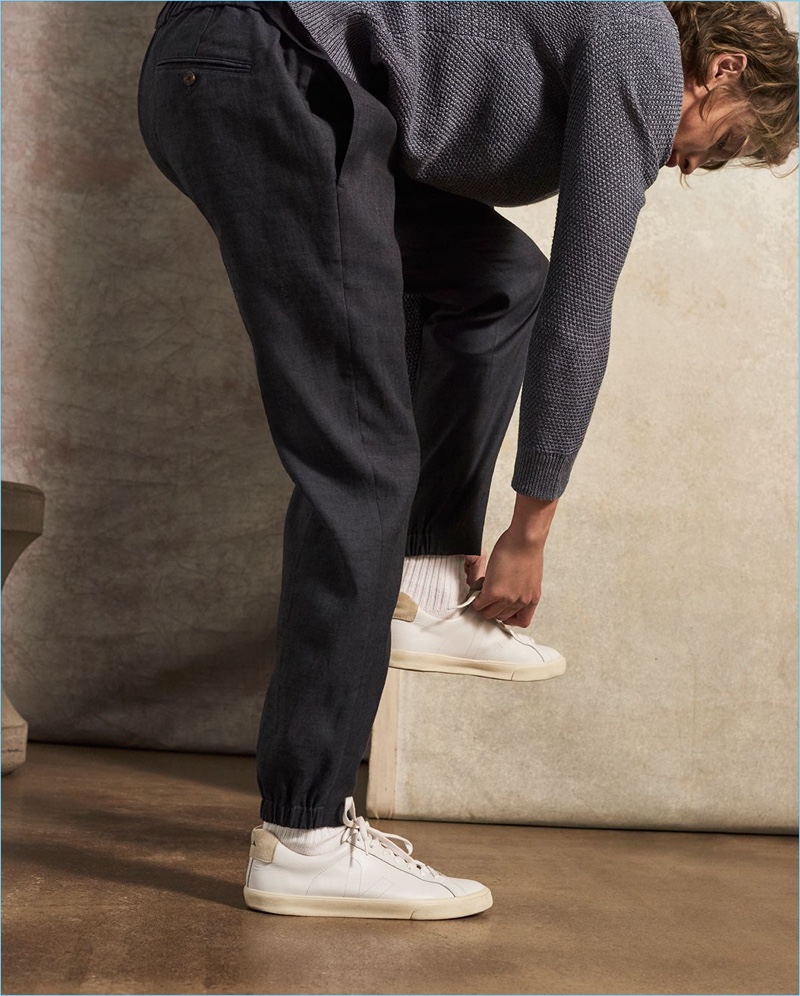 Tying his Veja sneakers, Lucas Satherley sports a Club Monaco linen sweater and trousers.