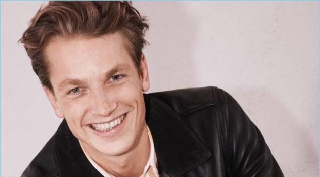 Hugo Sauzay Models Spring '18 Lineup by H&M Edition Smiling for the camera, Hugo Sauzay wears a yellow striped shirt with a H&M Edition leather biker jacket.