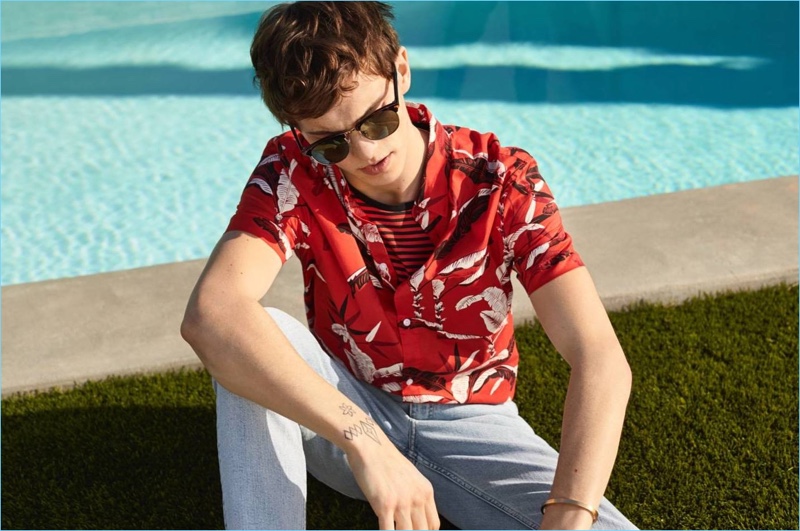 Embracing summer vibes, Luc Defont-Saviard rocks a H&M floral print shirt, striped tee, jeans, and sunglasses.