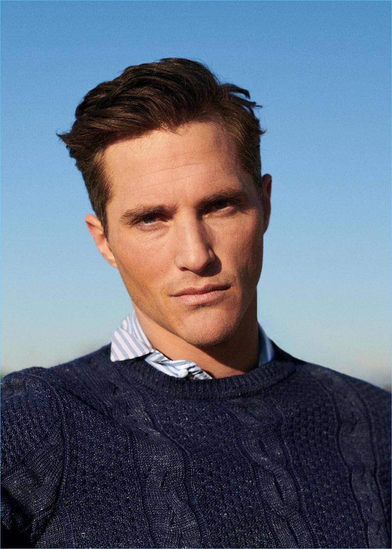 Embracing classic style, Ollie Edwards wears a cable-knit sweater and striped shirt from Mango.