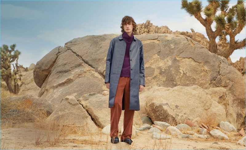 Benno Bulang wears a trench coat, turtleneck sweatshirt and straight-leg trousers by Sies Marjan. He also sports multi-strap leather sandals by Maison Margiela.