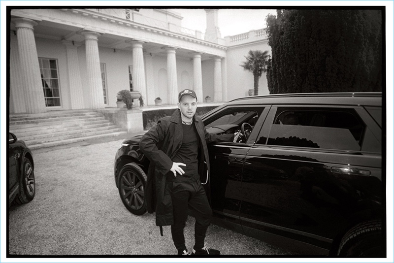 Connecting with Mr Porter, Mike Skinner sports a raincoat by TAKAHIROMIYASHITA TheSoloist. Skinner also wears a Prada suit jacket, Saint Laurent t-shirt, Y-3 sweatpants, and Balenciaga cap.