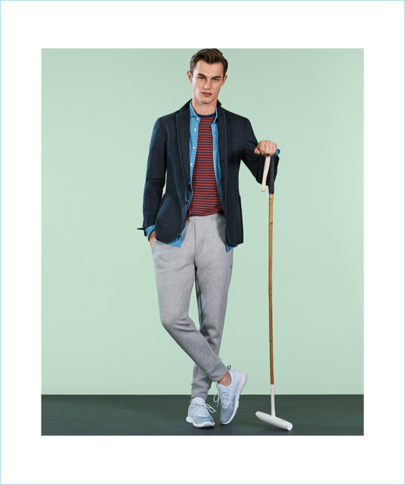 British model Kit Butler embraces timeless style in POLO Ralph Lauren. He wears a denim shirt, joggers, striped tee, sport coat, and sneakers.