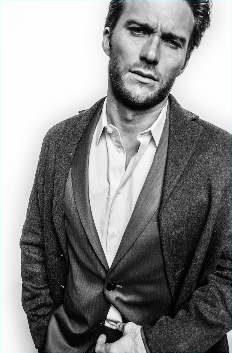 Appearing in a black and white photo, Scott Eastwood wears a Salvatore Ferragamo suit. He also dons an Acne Studios coat and Giorgio Armani shirt.