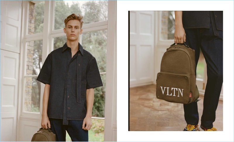 Oliver Houlby wears a Valentino denim short-sleeved shirt, paneled straight-leg jeans, and a VLTN-print canvas backpack. 