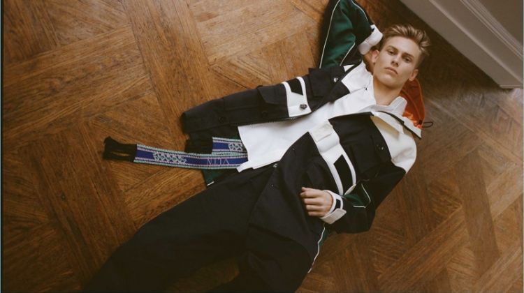 Oliver Houlby wears a Valentino parka, cotton-poplin shirt, logo-print chinos, and a multicolored logo-intarsia belt.