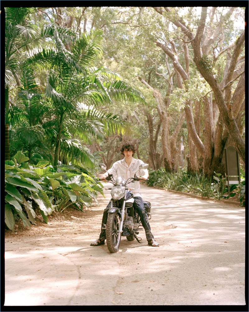 Taking a ride, Luca Lemaire wears a shirt and pants by Alexander McQueen with Prada sandals.