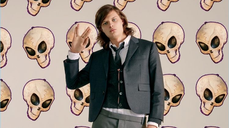 Showcasing a modern preppy side, Charlie Tahan wears Thom Browne. He dons a three-button sport coat, wool cardigan, skirt, and wingtip bluchers.