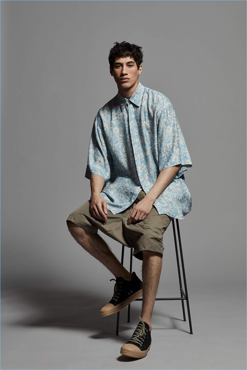 Model Malik Al Jerrari wears a Dries Van Noten oversized floral print shirt with Rick Owens shorts and suede sneakers.