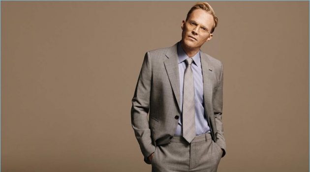 Donning grey, Paul Bettany wears a Stella McCartney virgin wool blazer and trousers with a Kingsman + Turnbull & Asser blue linen shirt. The actor also dons a Kingsman + Drake's checked silk tie and Kingsman + Cutler and Gross aviator-style optical glasses.