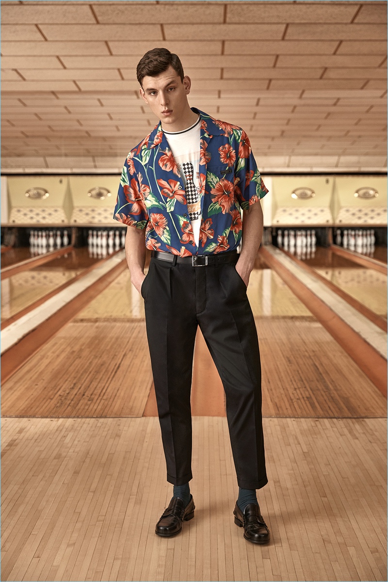 Ready for a summer holiday, Luke Farley wears a tropical print camp collar shirt from Prada. He also sports the label's graphic tee and tapered trousers.