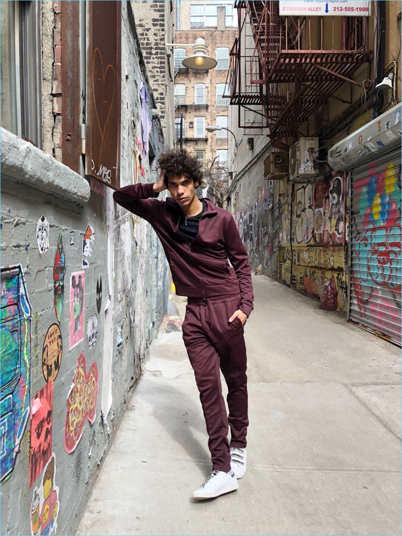 Alexis Ordoñez wears a burgundy track jacket and joggers from River Island's Concept collection.