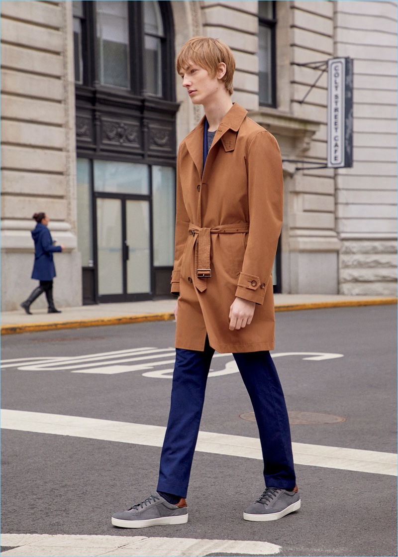 Honza Stiborek sports an Ermenegildo Zegna trench coat, herringbone suit, sweater, and suede sneakers. 