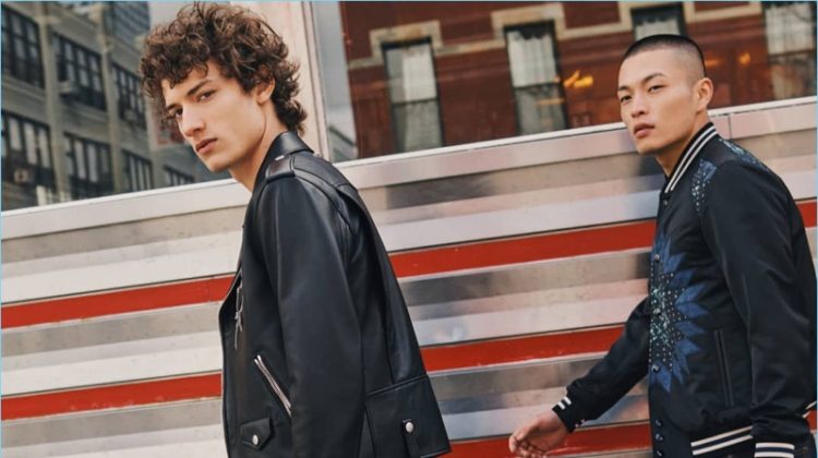 Left to Right: Serge Rigvava wears a Coach 1941 moto jacket in black. Satoshi Toda models a Coach 1941 patchwork varsity jacket. Both models carry Coach's Metropolitan Portfolio leather bag.