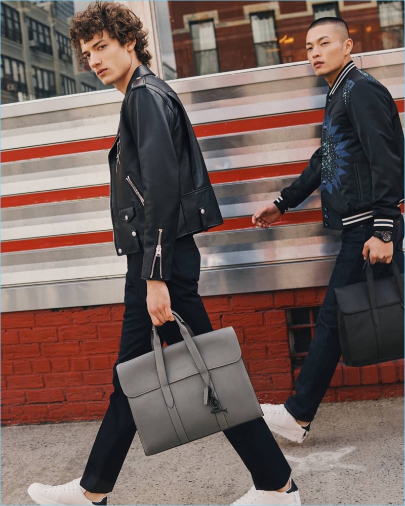 Left to Right: Serge Rigvava wears a Coach 1941 moto jacket in black. Satoshi Toda models a Coach 1941 patchwork varsity jacket. Both models carry Coach's Metropolitan Portfolio leather bag.