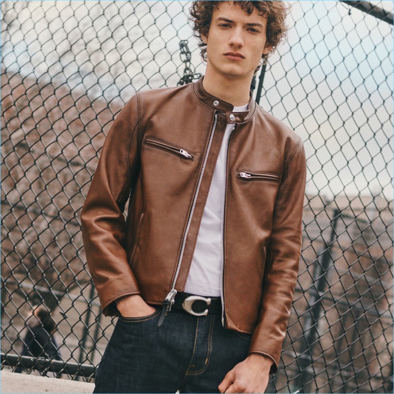 Serge Rigvava rocks a brown leather racer jacket by Coach 1941. He also sports the brand's sculpted signature belt.