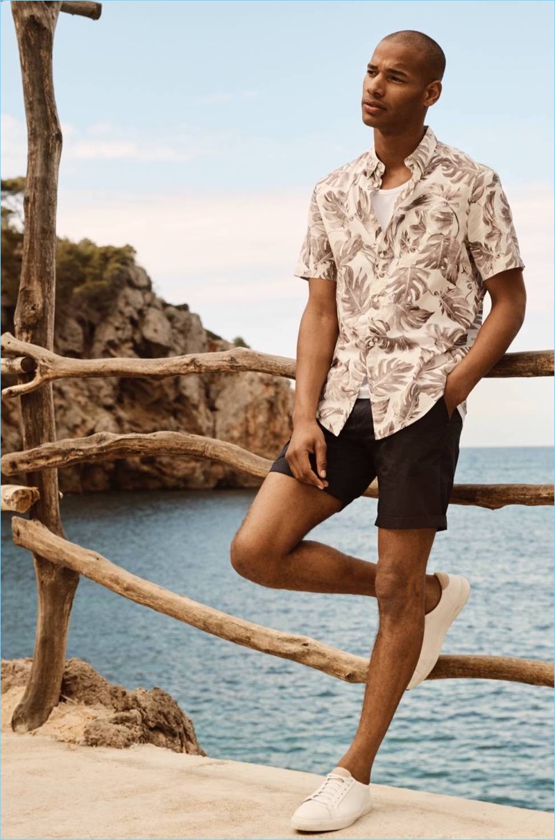 Connecting with H&M, Sacha M'Baye wears a patterned short-sleeve shirt with chino shorts.