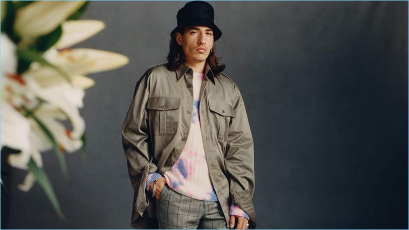 Héctor Bellerín wears a Dries Van Noten oversized shirt with Raf Simons trousers and a tie-dyed sweater by The Elder Statesman. He also sports a Prada bucket hat.