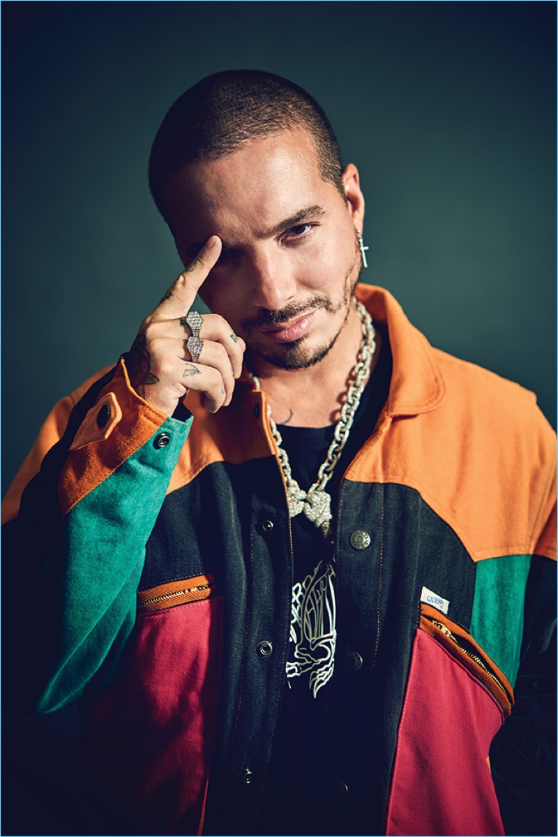 Front and center, J Balvin wears a Guess x J Balvin and Dr. Romanelli jacket, Gef x J Balvin t-shirt, Ben Baller diamond rings and a Ben Baller x Kaws diamond necklace.