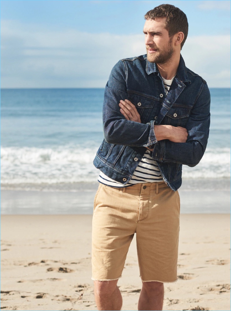 Taking to the beach, Will Chalker wears J.Crew's 9" distressed officer's shorts in golden khaki.