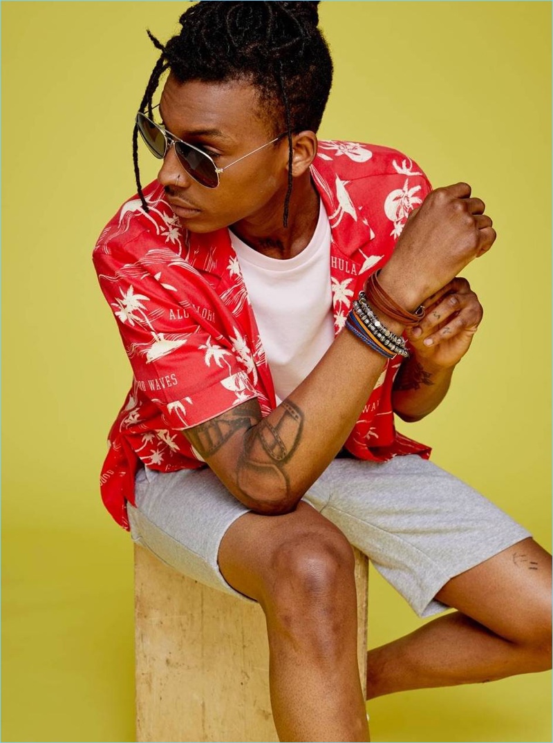 Matthew Davidson wears a red tropical print shirt with a t-shirt, sweatshorts, and sunglasses by H&M.