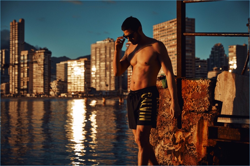 Watching the sun go down, René Grincourt models a pair of Calvin Klein swim shorts.