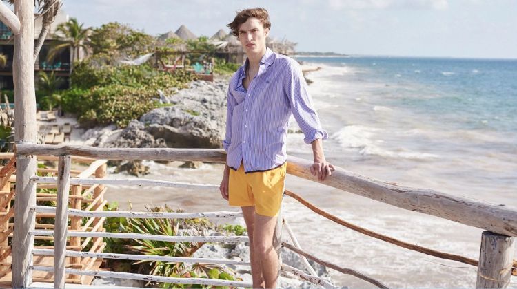 Embracing summer style, Tim Dibble wears a Lanvin striped shirt, Marané swim shorts, and a logo charm necklace by Saint Laurent.