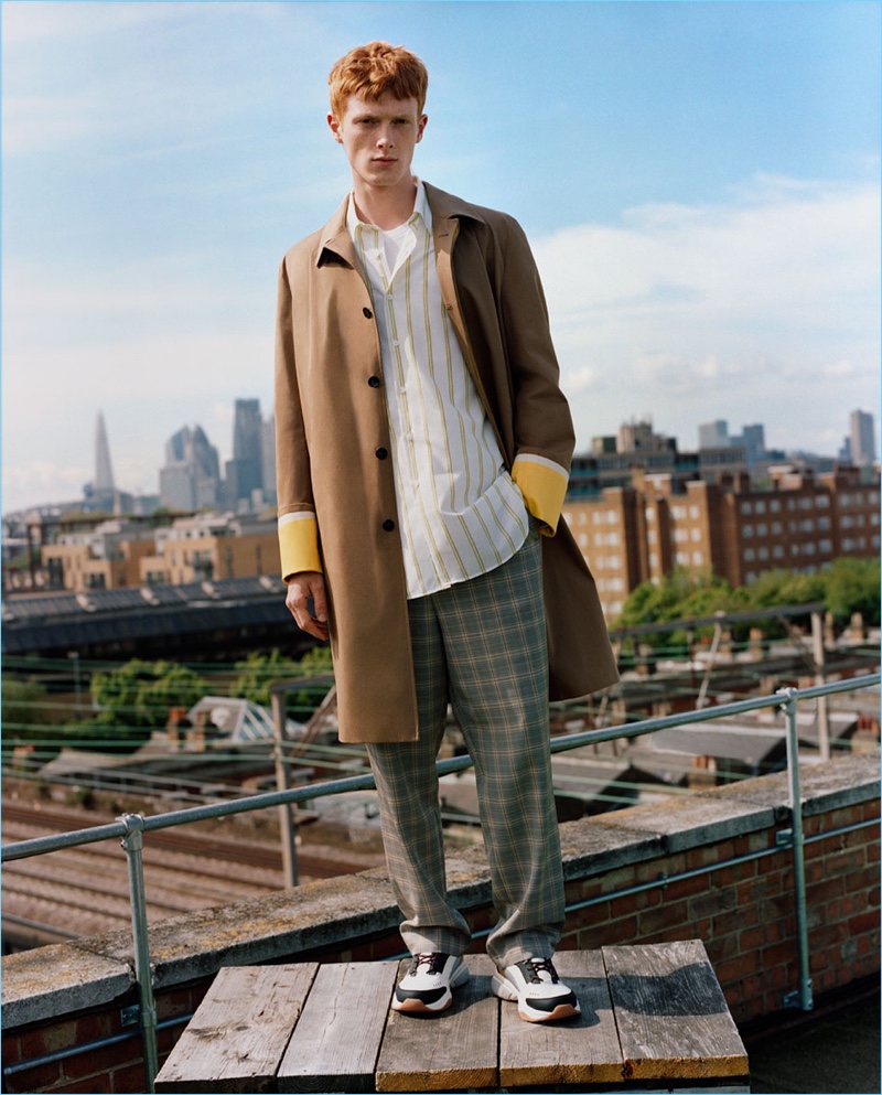 Linus Wordemann dons a car coat with a striped shirt, check pants, and sneakers from Zara Man.