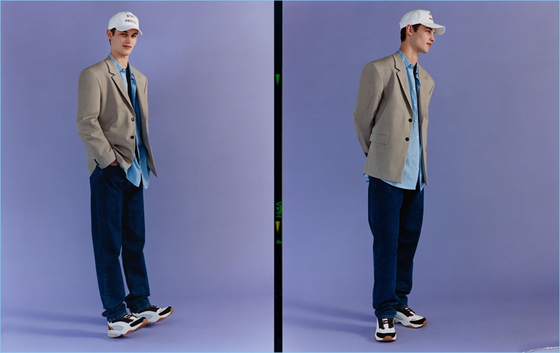 Kit Butler dons relaxed jeans with a shirt, blazer, sneakers, and a cap from Zara Man.