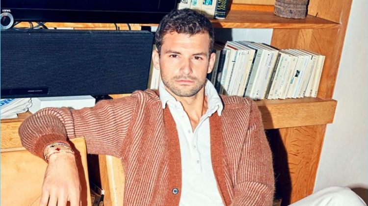 Relaxing, Grigor Dimitrov sports a Lanvin cardigan, Massimo Alba polo, and white Burberry jeans.