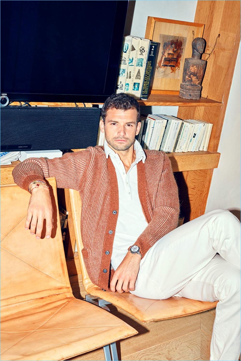 Relaxing, Grigor Dimitrov sports a Lanvin cardigan, Massimo Alba polo, and white Burberry jeans.