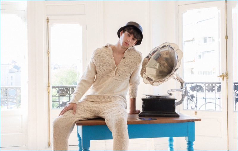 Sporting a bucket hat, Oscar Ruebman wears light colored knitwear by Loewe.