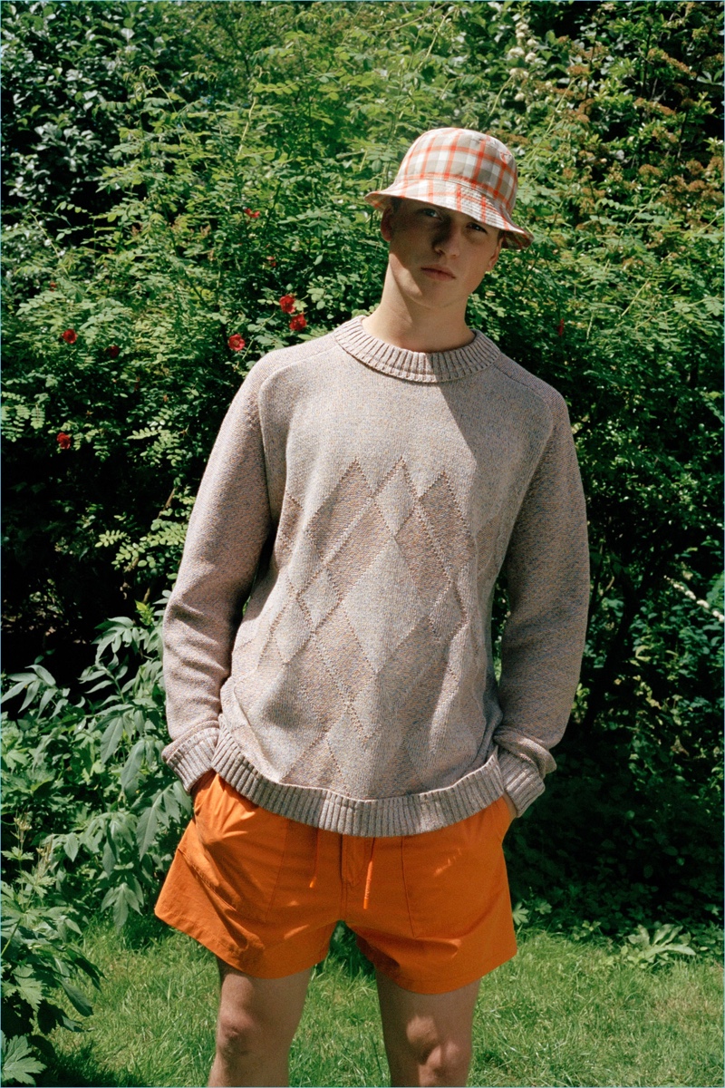 Model Hamish Frew wears an argyle sweater with orange shorts and a bucket hat from Pringle of Scotland.