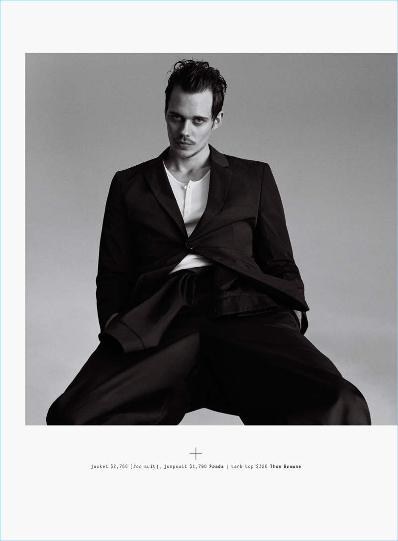 A chic vision, Bill Skarsgård dons a Prada suit jacket and jumpsuit with a Thom Browne tank.