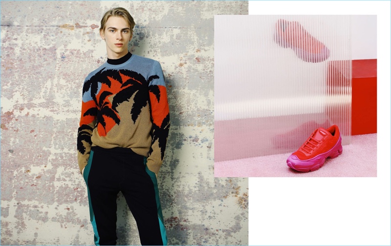 A chic vision, Dominik Sadoch dons a Hawaiian print sweater from Valentino. The blond model also sports a Givenchy t-shirt and Lanvin track pants. Pictured right: Raf Simons x Adidas sneakers. 