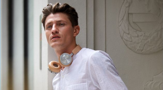 Stepping out in style, Eli Hall models a Theory pinstripe shirt with Obey shorts. The model also sports a Miansai wrap bracelet and Bang & Olufsen H8i wireless headphones.