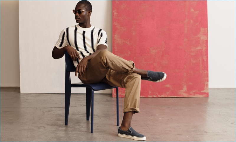 Embracing summer style, Charles Oduro wears a striped J.Crew top, stretch chinos, and sunglasses with Vans slip-on sneakers.