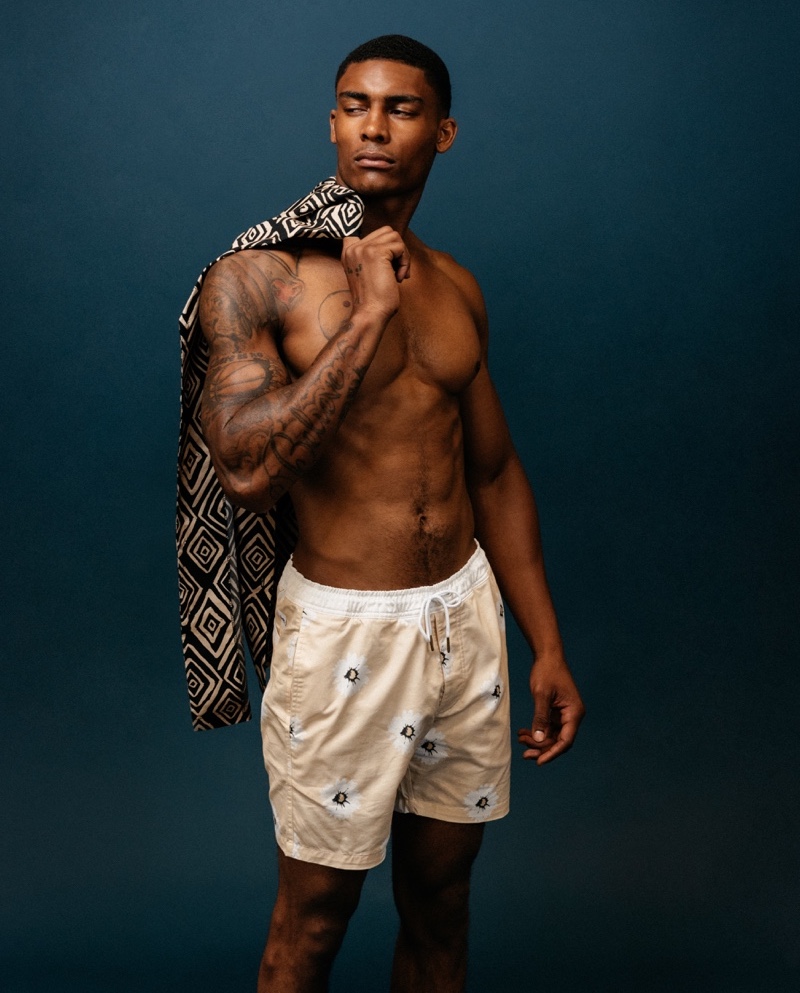 Taejahn wears Marrakech swim shorts in stone,  Mbatau shirt in black TeeInk / Charlie Holiday.