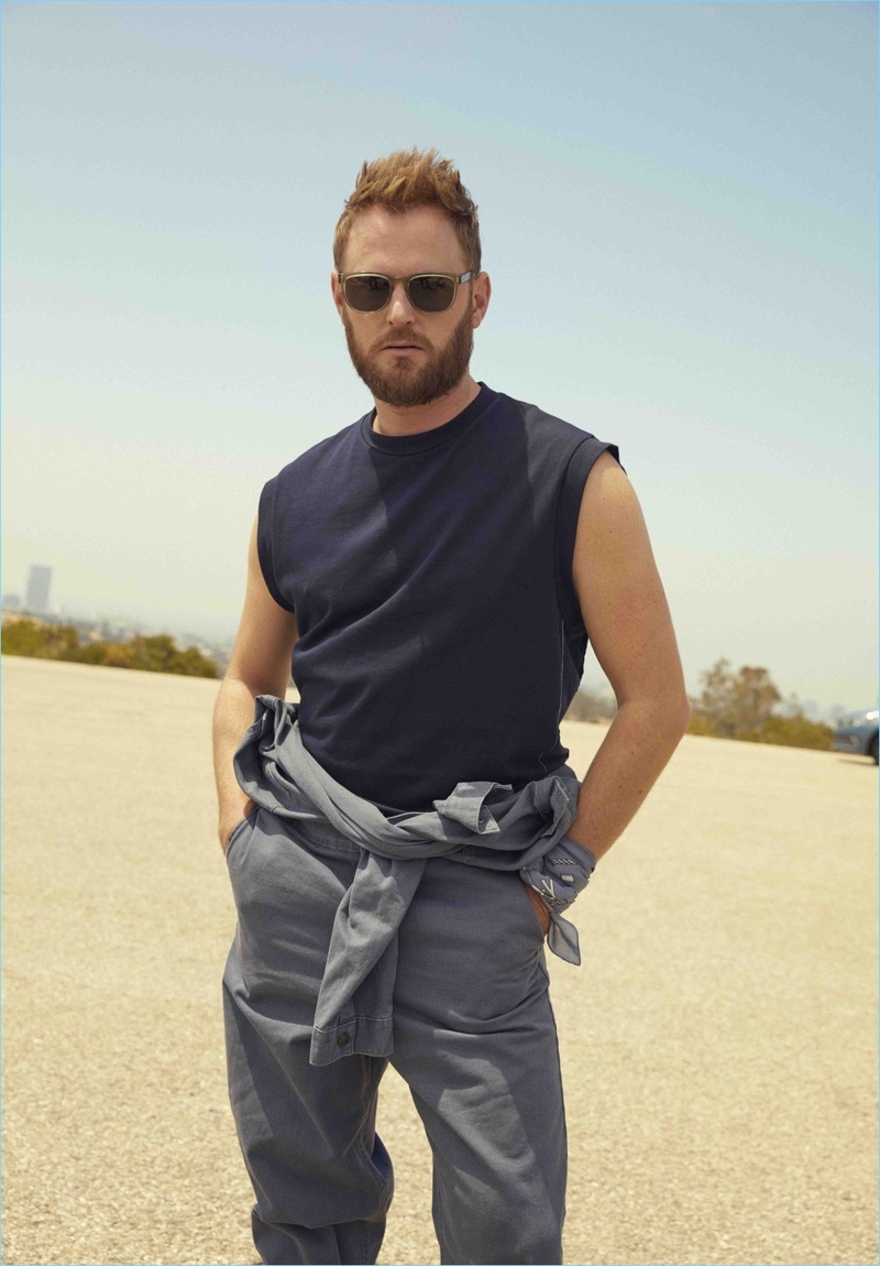 Bobby Berk wears a 3.1 Phillip Lim t-shirt, Topman jumpsuit, and BOSS scarf (worn on his wrist).