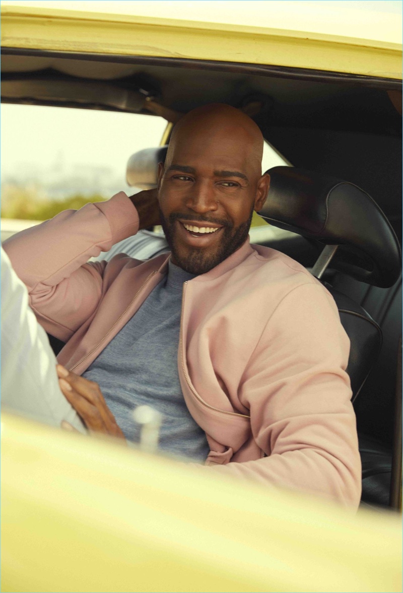 Karamo Brown sports a BOSS sweater, COS bomber jacket, and Stella McCartney trousers.