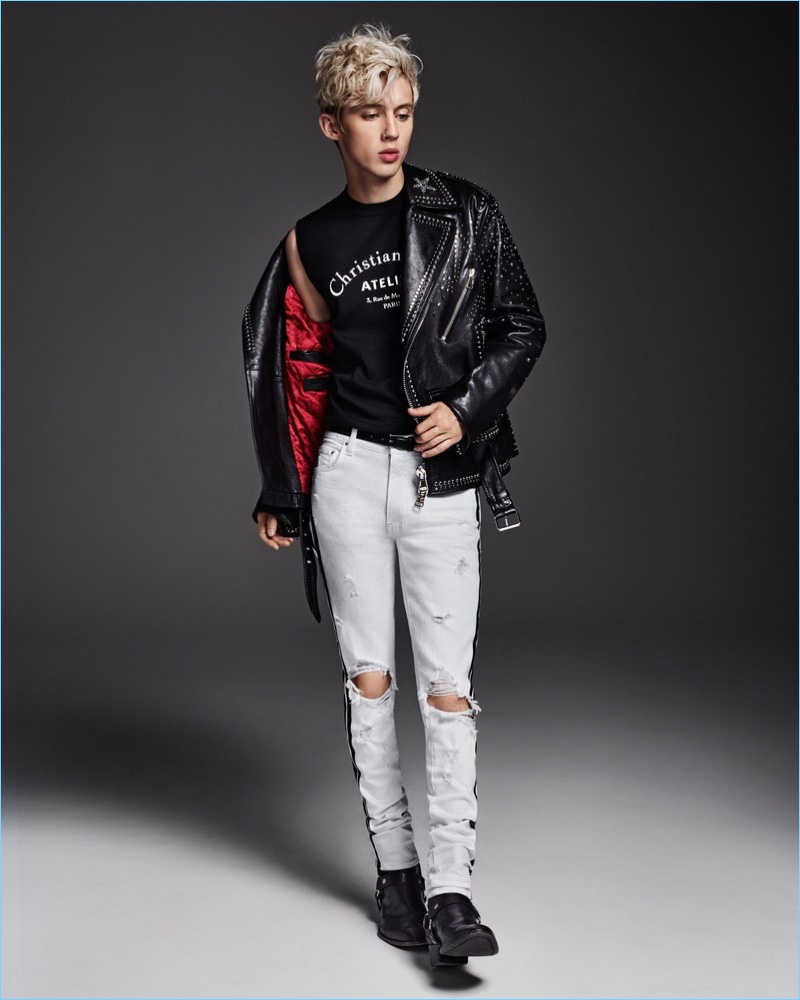 A cool vision, Troye Sivan wears a sleeveless Dior Homme sweater with a Valentino leather biker jacket. He also rocks Amiri jeans and Saint Laurent boots.