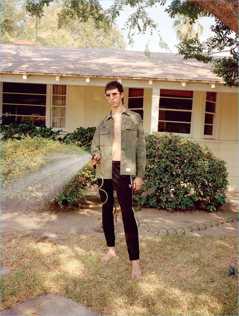 Maintaining a casual cool, John Swiatek sports a WTAPS shirt, Adidas track pants, and BLYSZAK sunglasses.